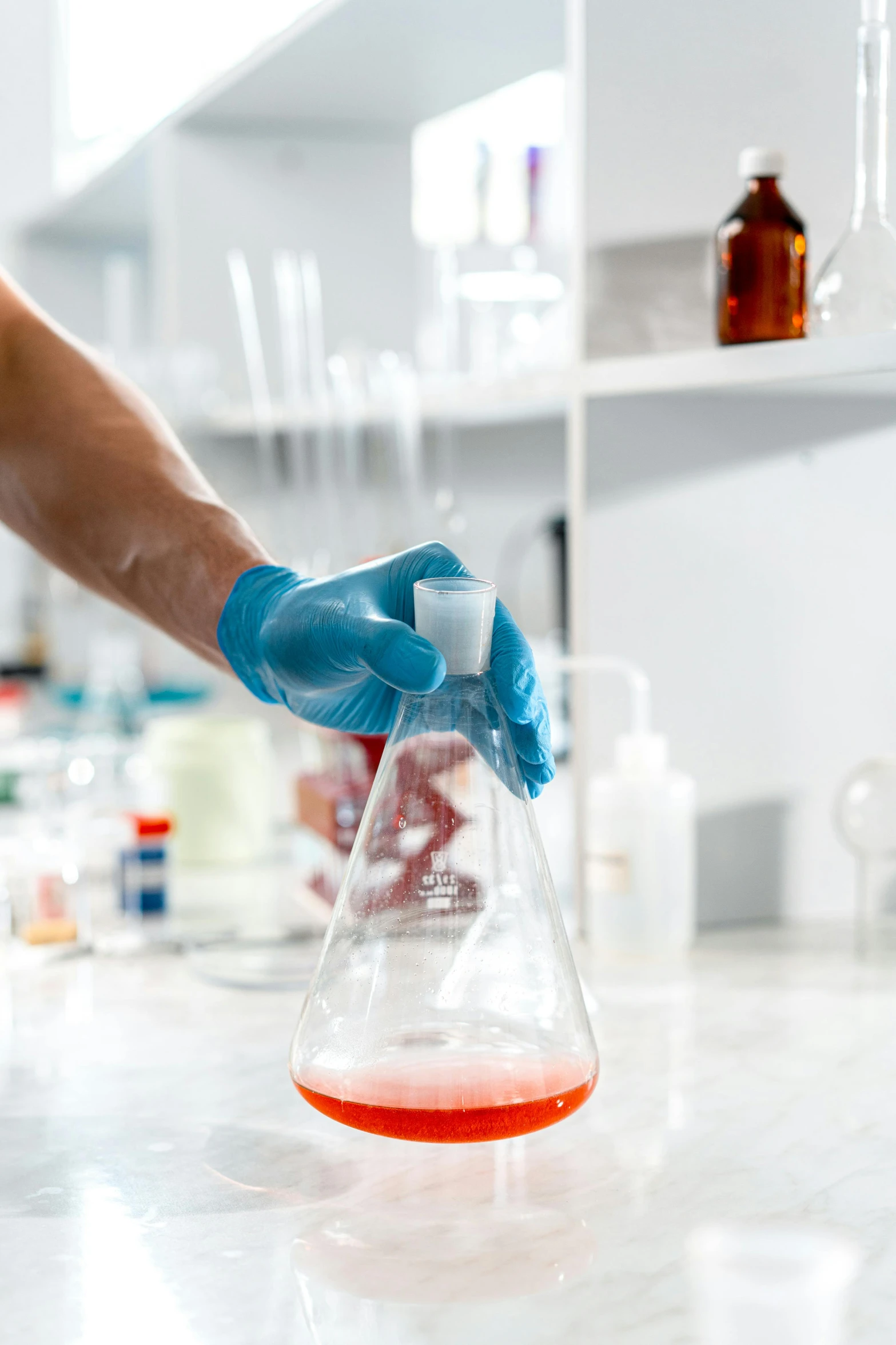 a person in blue gloves holding a beaker filled with liquid, shutterstock, instagram post, a wide shot, red liquid, college