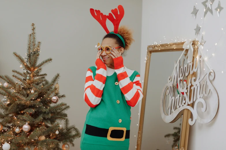 a woman standing in front of a christmas tree, a cartoon, trending on pexels, hurufiyya, wearing round glasses, elf, outfit photo, antlers