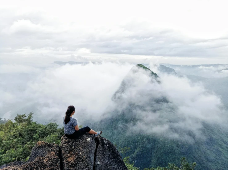 a woman sitting on top of a large rock, by Max Dauthendey, pexels contest winner, cloud forest, view above the clouds, avatar image, assamese aesthetic