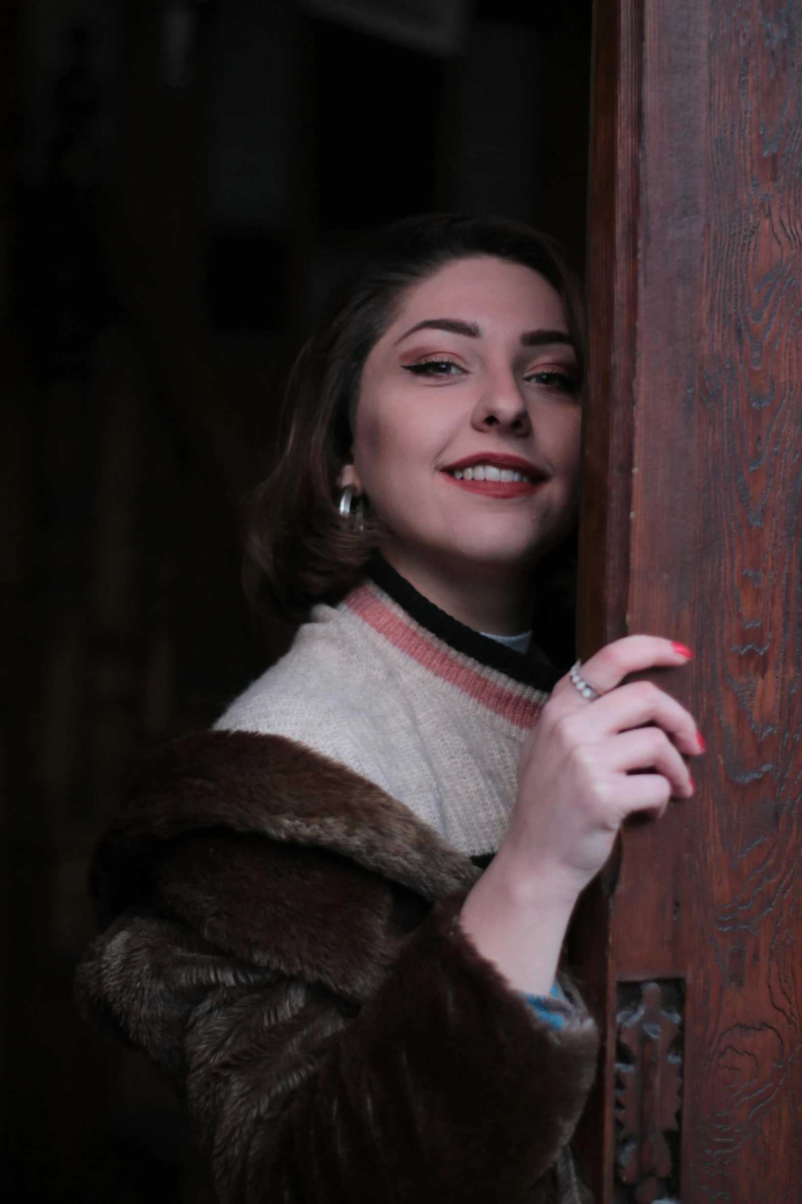 a woman in a fur coat opening a door, inspired by Elsa Bleda, pexels contest winner, renaissance, smiling young woman, ( ( theatrical ) ), maria callas, pale ivory skin