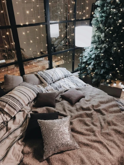 a bed sitting in a bedroom next to a christmas tree, by Anna Haifisch, pexels contest winner, glitter gif, brown and white color scheme, amazing view, 🌲🌌