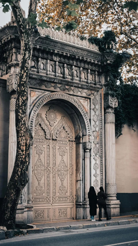 a couple of people standing in front of a building, by Riad Beyrouti, unsplash contest winner, art nouveau, walking out of a the havens gate, carved into the side of a tree, thumbnail, high quality photo