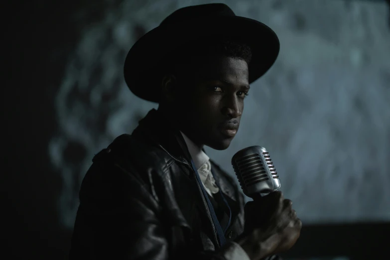 a man in a hat holding a microphone, dark skinned, moody iconic scene, production still, taken with sony alpha 9