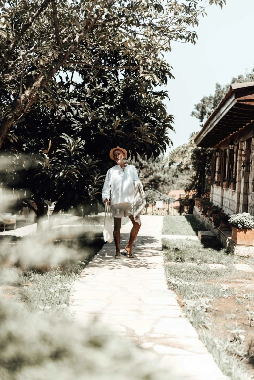 a man walking down a sidewalk next to a building, cottagecore hippie, bali, woman posing, instagram photo