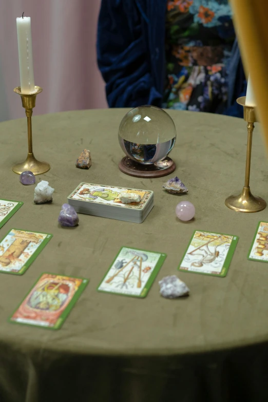 a table with cards and candles on it, a hologram, by Jan Cox, renaissance, crystal ball, focus on card, robed figures sat around a table, pair of keycards on table