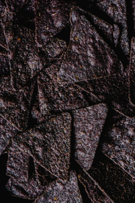 a pile of tortilla chips sitting on top of a table, pexels contest winner, australian tonalism, high resolution coal texture, dark purple, made of lava, issey miyake
