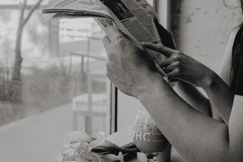 a woman sitting at a table reading a newspaper, a black and white photo, pexels contest winner, standing near a window, gif, hands, ad image