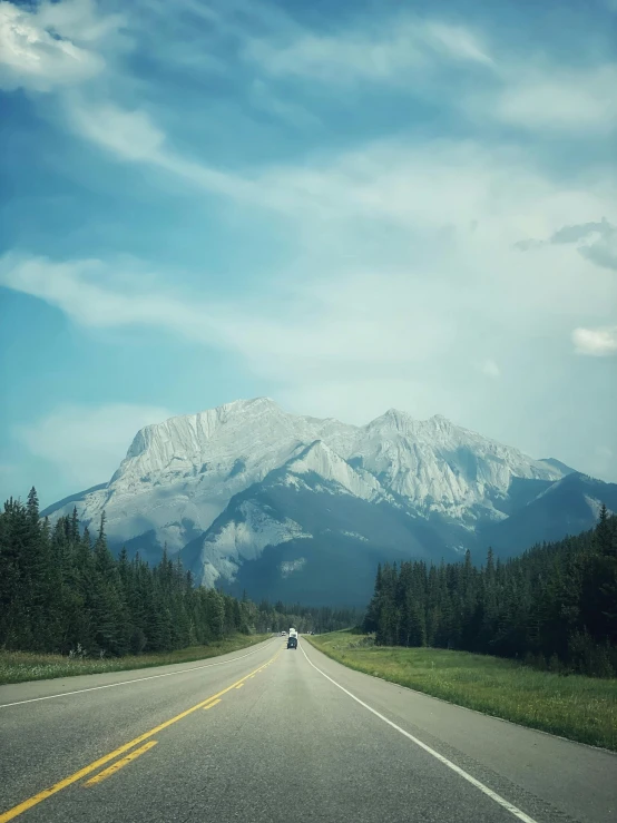 a car driving down a road with a mountain in the background, by Brigette Barrager, pexels contest winner, banff national park, conde nast traveler photo, photo taken on fujifilm superia, instagram photo