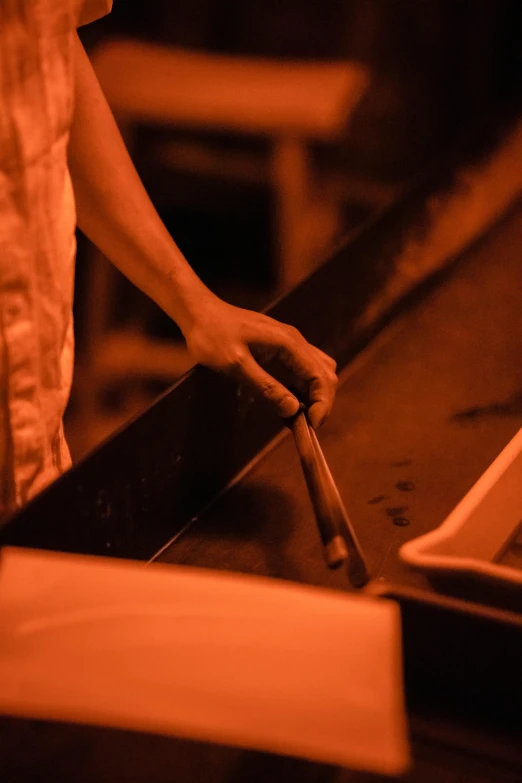 a close up of a person cooking food on a grill, a silk screen, unsplash, process art, holding magical kitchen knives, in a butcher shop, warm lighting inside, metalwork