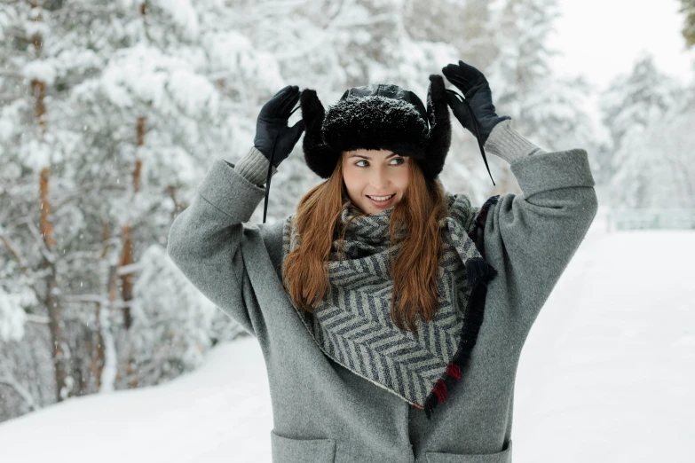 a woman standing in the snow with her hands on her head, pexels contest winner, excited russians, black pointed hat, thumbnail, grey