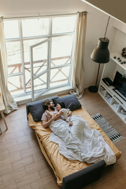 a person laying on a bed in a room, couple, inside a cozy apartment, commercially ready, bird view