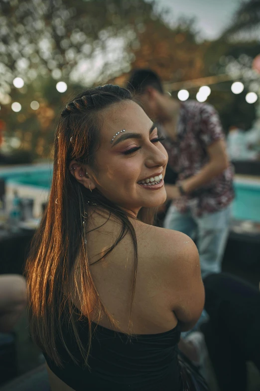 a woman in a black dress standing next to a pool, trending on pexels, happening, disco smile, girl with plaits, college party, head bent back in laughter