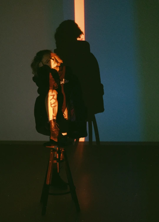 a person sitting in a chair in a dark room, an album cover, inspired by Nan Goldin, unsplash, visual art, two figures wearing gas masks, backlit shot girl in parka, casting long shadows, alberto seveso and dan mccaw