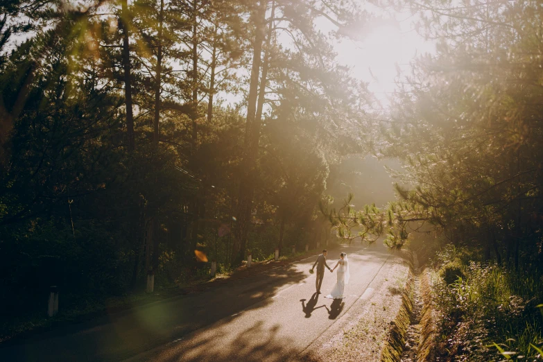 a couple of people riding skateboards down a road, a picture, by Marshall Arisman, unsplash contest winner, wedding, pine forests, morning sunlight, bali