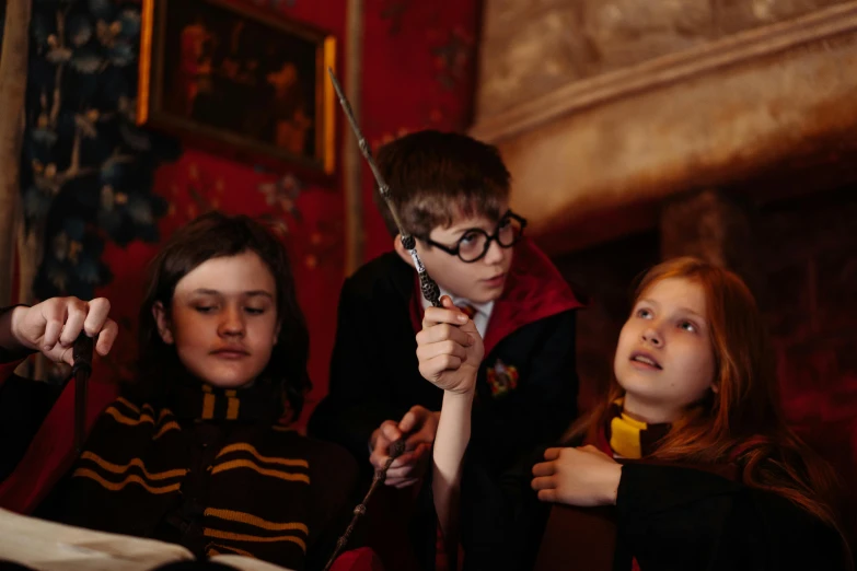 a group of young children sitting next to each other, by Sylvia Wishart, hogwarts gryffindor common room, casting a spell, close up portrait shot, promo image