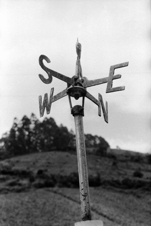 a black and white photo of a weather vane, by Dorothea Lange, 1907, found on a volcano, directions, marker”