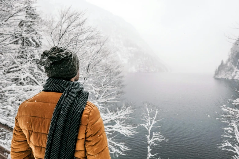 a person standing in front of a body of water, cold weather, looking in front, guide, multiple stories