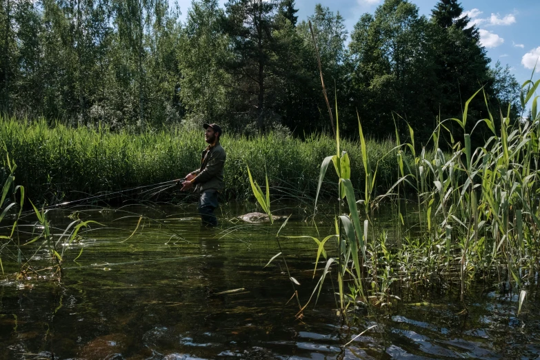 a man standing in the water with a fishing rod, by Jaakko Mattila, hurufiyya, lush surroundings, no cropping, alessio albi, professional photo