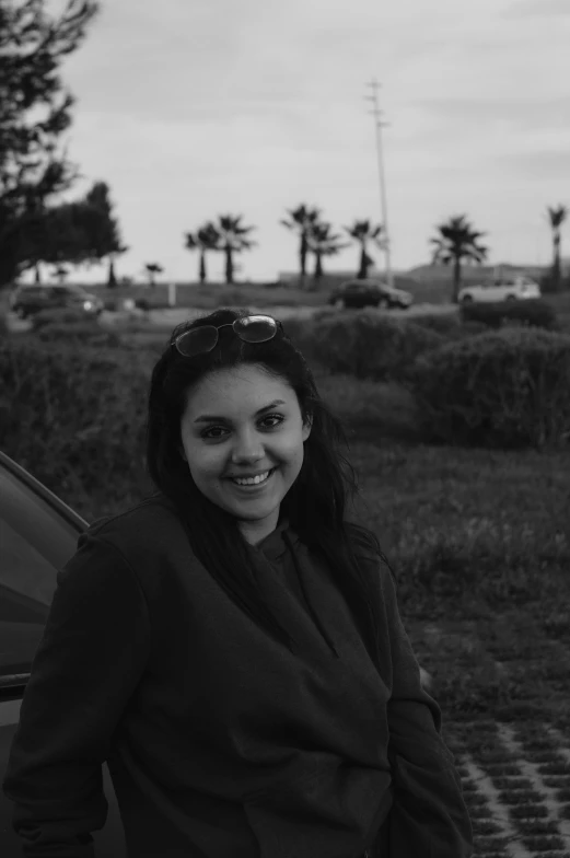 a woman standing next to a parked car, a black and white photo, kyza saleem, headshot profile picture, at the seaside, ((portrait))