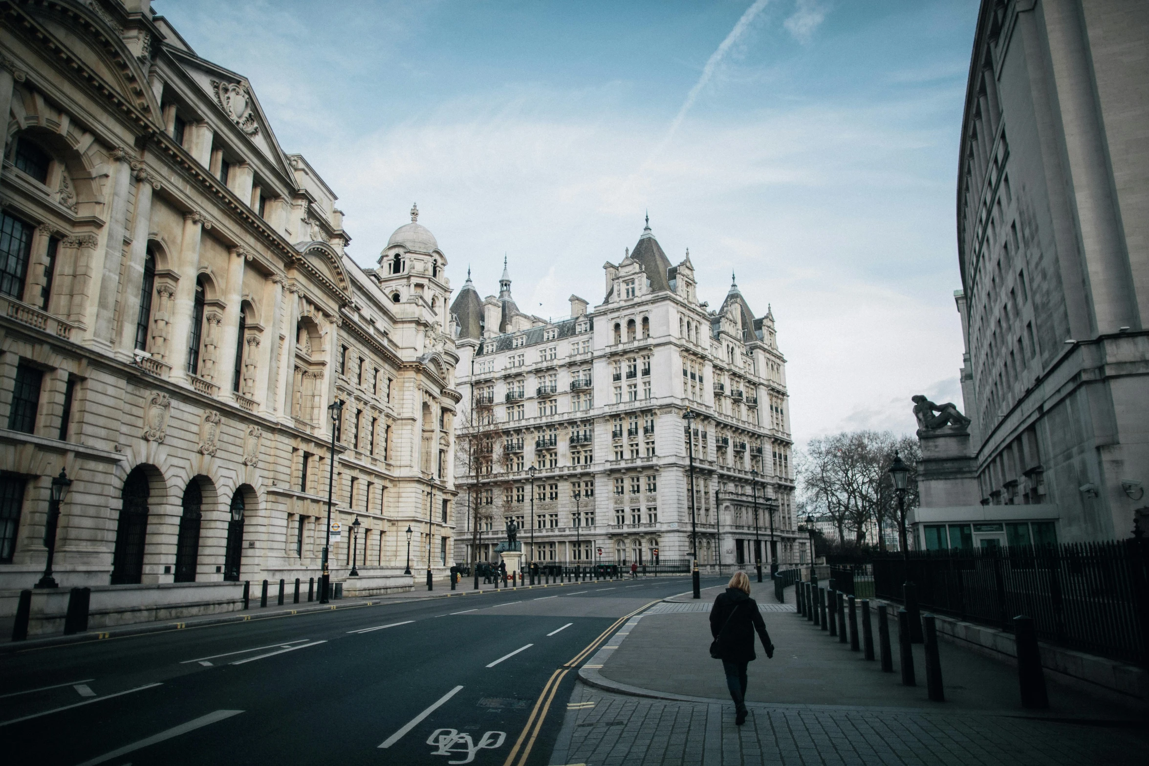 a person walking down a street next to tall buildings, inspired by Christopher Wren, unsplash contest winner, baroque, houses of parliament, on a great neoclassical square, liz truss, exterior shot