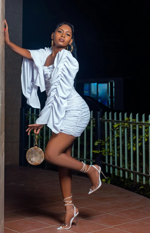 a woman in a white dress leaning against a wall, an album cover, by Chinwe Chukwuogo-Roy, pexels contest winner, doing a sassy pose, 15081959 21121991 01012000 4k, nigth, 2 4 year old female model