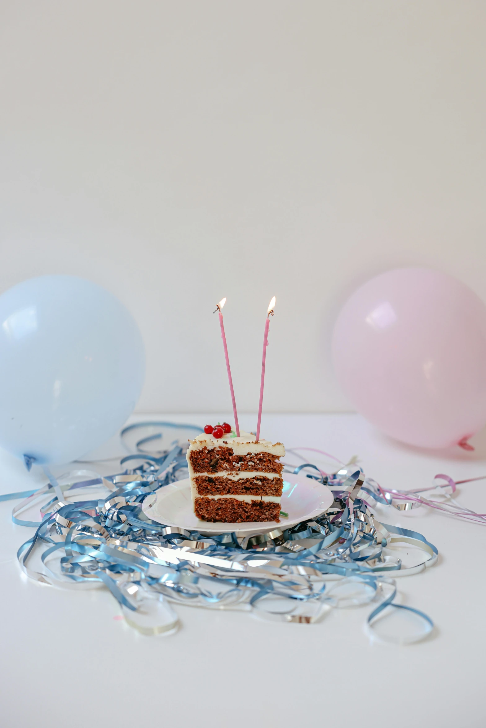 a piece of cake sitting on top of a plate, by Alice Mason, unsplash, happening, party balloons, light blue and white tones, white candles, pink