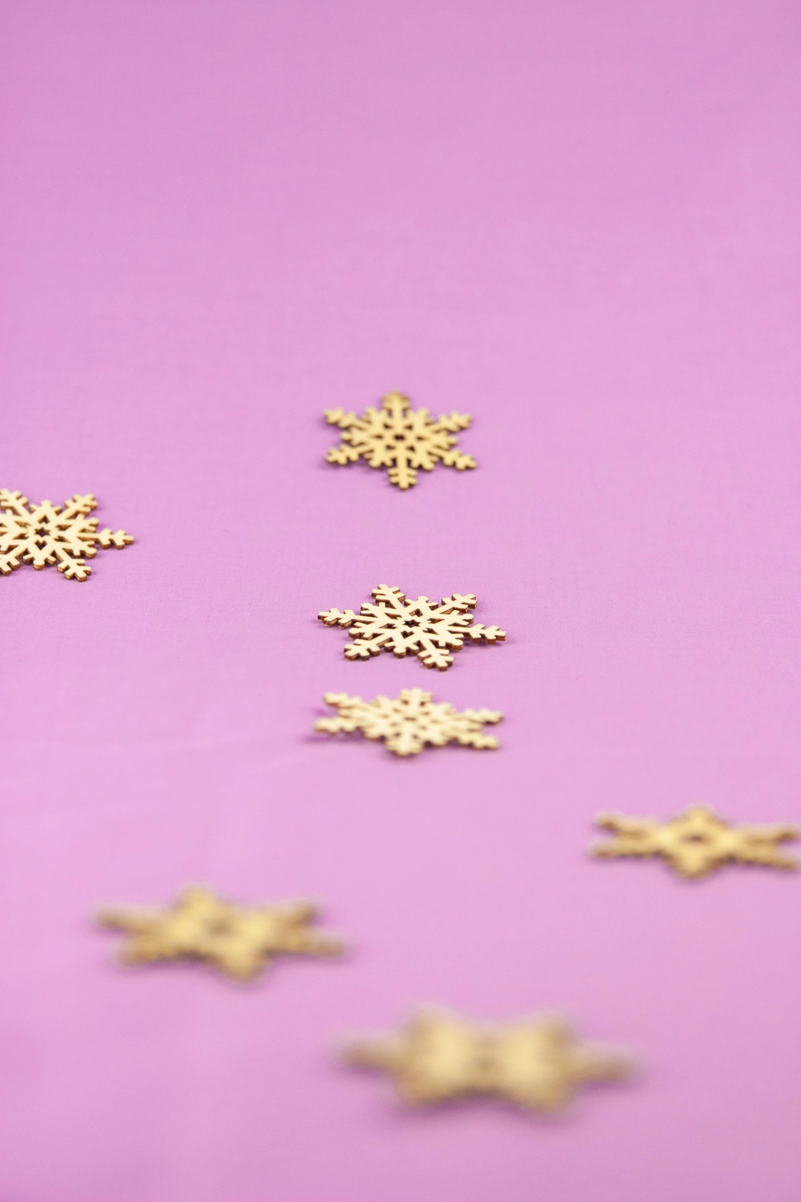 gold snowflakes on a purple background, trending on pexels, process art, mini model, pink background, wooden decoration, light scatter