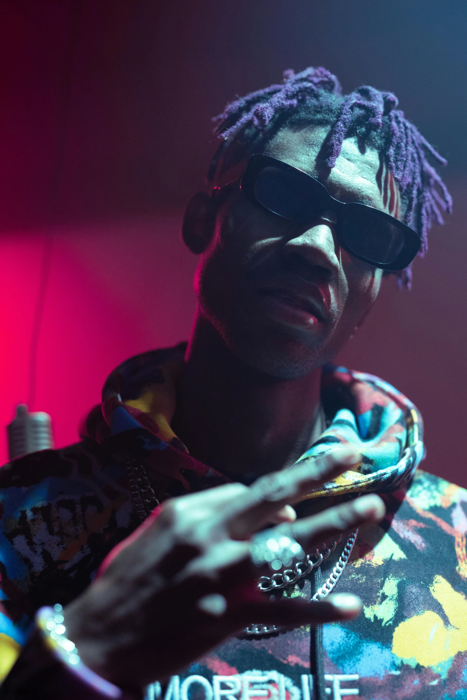 a man in a colorful jacket and sunglasses, an album cover, trending on pexels, 2 1 savage, dramatic lighting; 4k 8k, ( ( theatrical ) ), performing a music video