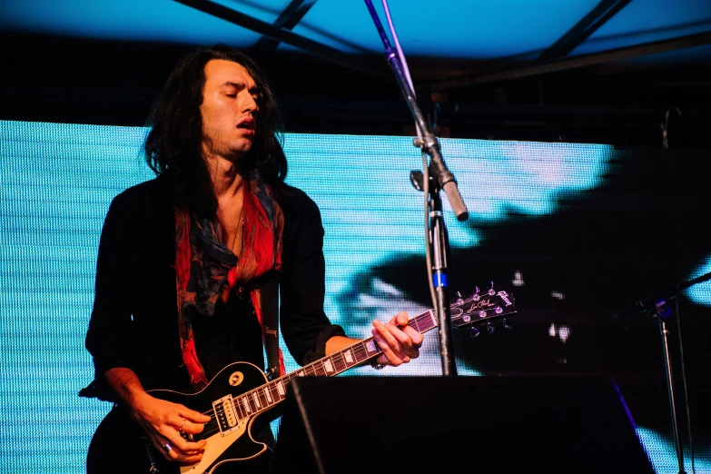 a man with long hair playing a guitar, antipodeans, profile image, on a stage, lachlan bailey, slide show