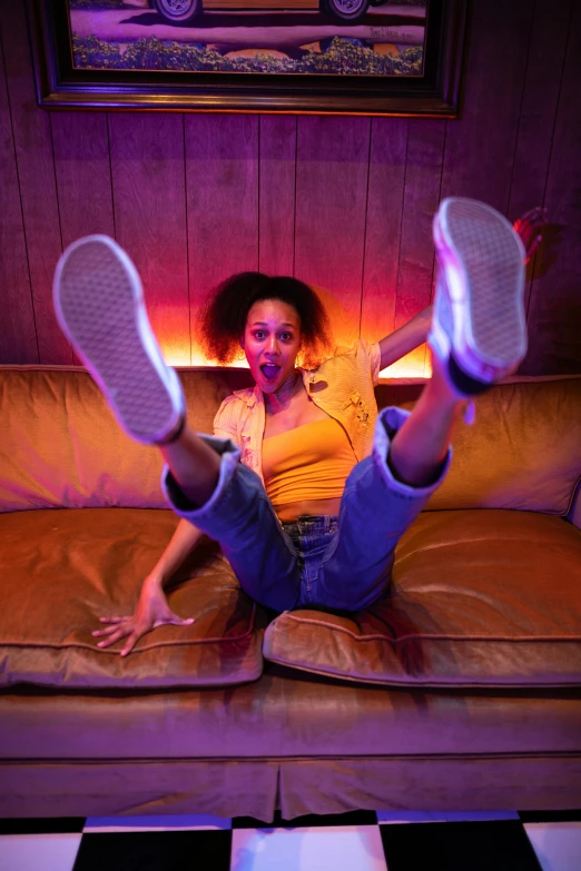 a woman sitting on a couch with her legs in the air, happening, ashteroth, nightlife, duck shoes, tongue out