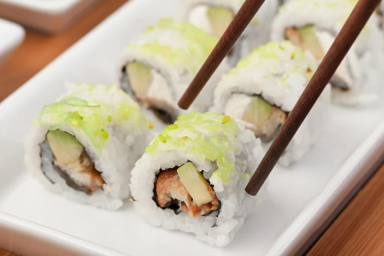 a white plate topped with sushi and chopsticks, pastel green, square, medium angle, image