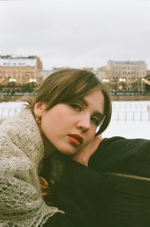 a woman sitting on top of a bench next to a body of water, an album cover, inspired by Vasily Perov, trending on pexels, realism, big cheekbones, winter, sovietwave aesthetic, soft oval face