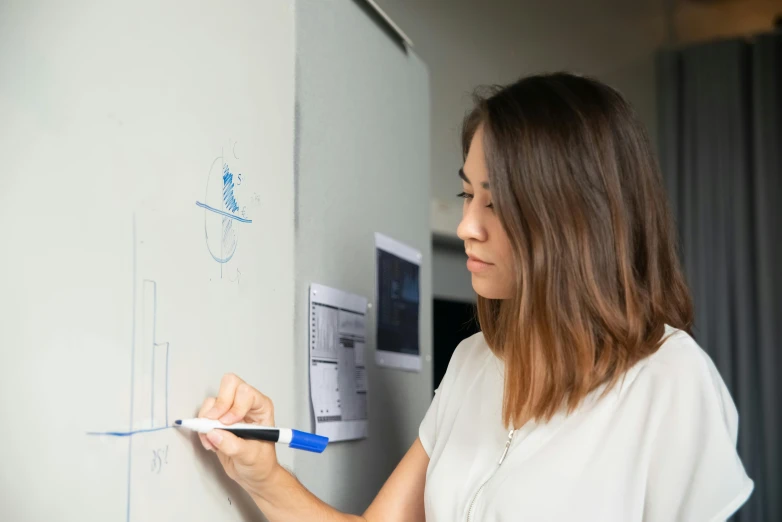 a woman is writing on a white board, pexels contest winner, blueprint schematics, posed in profile, in office, indi creates