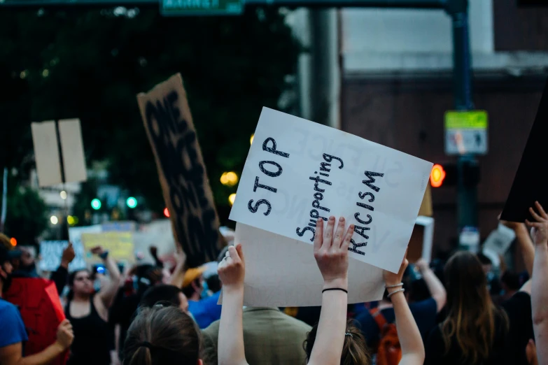 a group of people holding up signs in the air, by Carey Morris, trending on unsplash, xenophobia, during the night, violent protest, promo image