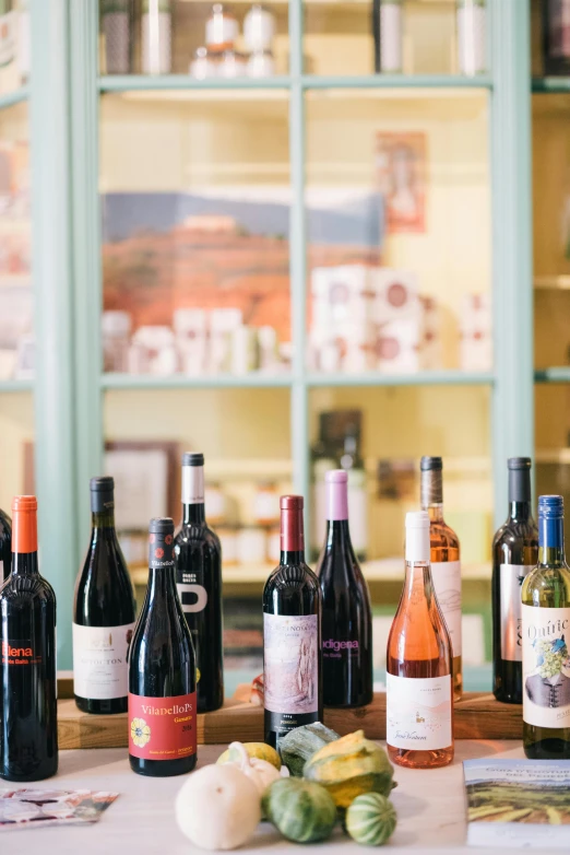 a table topped with lots of bottles of wine, wine label, colorful with red hues, lined up horizontally, product shot