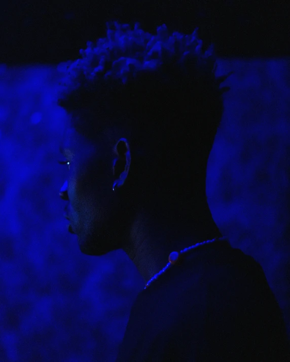 a close up of a person in a dark room, an album cover, inspired by Frank Mason, unsplash, afrofuturism, high blue lights, 2 1 savage, bisexual lighting, profile image