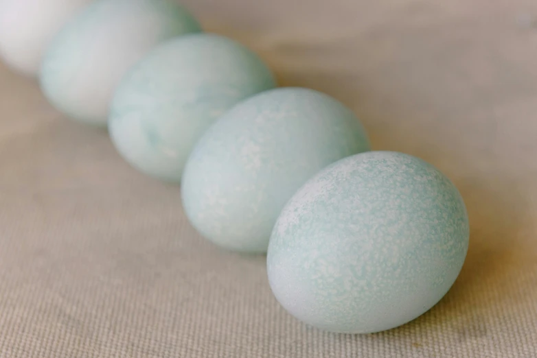 a row of eggs sitting on top of a table, glistening seafoam, a daub of cold blue, subtle detailing, up close shot