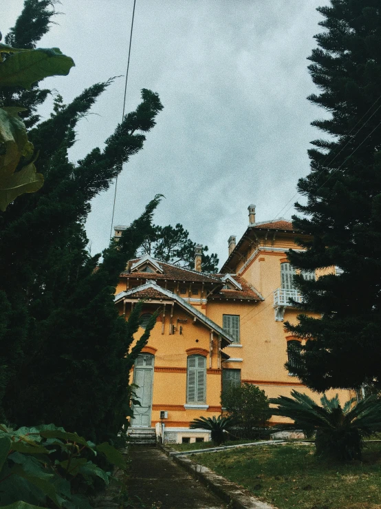 a yellow house surrounded by trees on a cloudy day, by Andrée Ruellan, unsplash contest winner, art nouveau, cannes, after the storm, low quality photo, overcast!!!