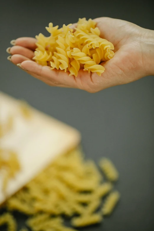 a person holding a handful of pasta in their hand, inspired by Géza Dósa, petals, close up details, 8l, amanda lilleston