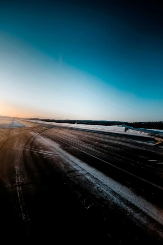 an airplane taking off from an airport runway, by Tobias Stimmer, pexels contest winner, conceptual art, lapland, wide roads, cold sunset, clear sky above