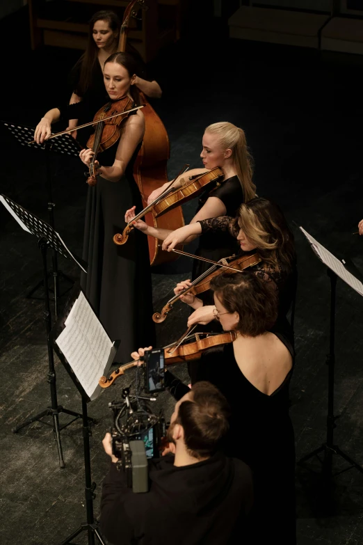 a group of people that are playing musical instruments, standing on top of a violin