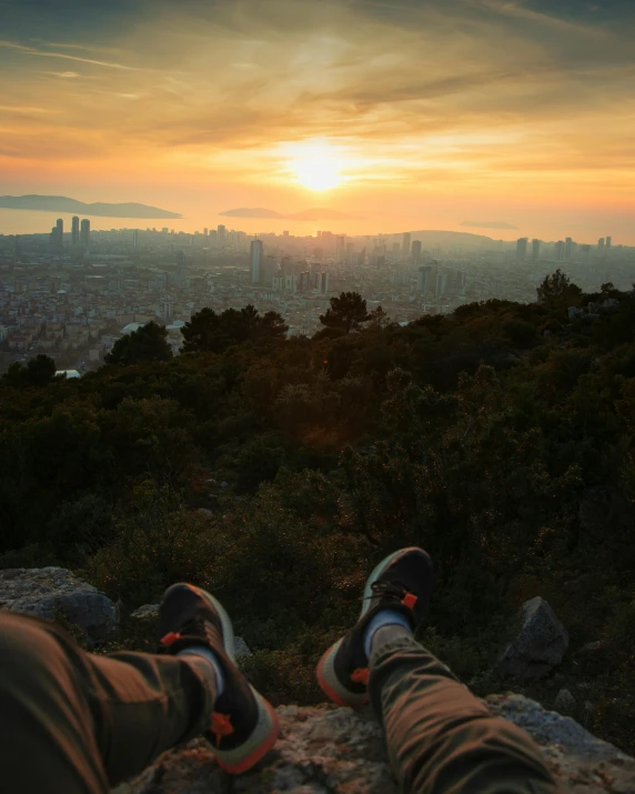 a pair of feet that are sitting on a rock, by Niko Henrichon, pexels contest winner, happening, city sunset, lush vista, barcelona, a photo of a man