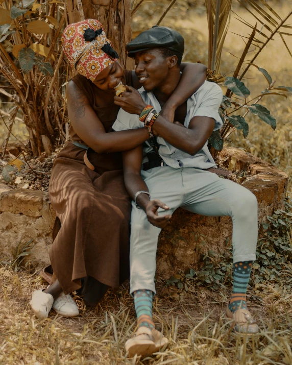 a man and a woman sitting next to each other, by Ingrida Kadaka, pexels contest winner, happening, with brown skin, lush surroundings, lgbtq, african iconography