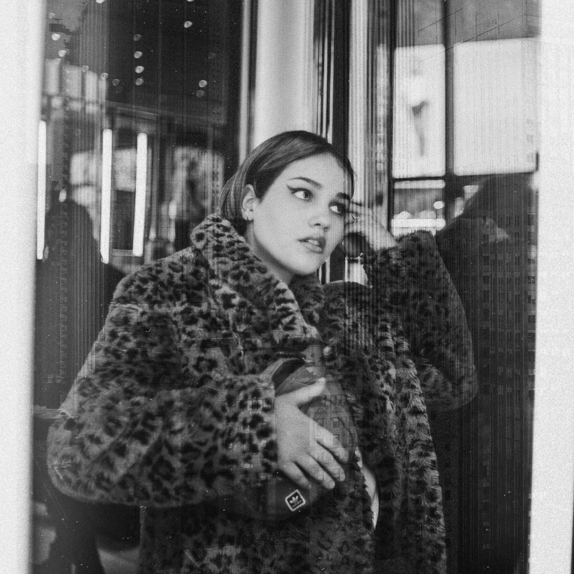 a black and white photo of a woman in a leopard print coat, pexels, realism, with a mirror, arab young monica belluci, 35mm of a very cute, wearing a luxury fur coat