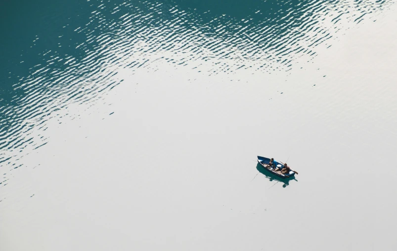 a small boat floating on top of a large body of water, by Yasushi Sugiyama, pexels contest winner, minimalism, nepal, people angling at the edge, taken from a plane, low colour