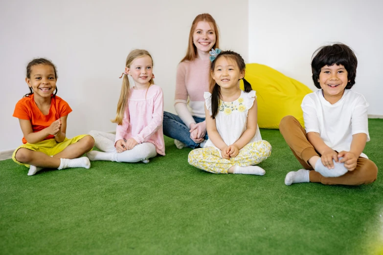 a group of children sitting on the floor in a room, on a green lawn, abcdefghijklmnopqrstuvwxyz, manuka, on a yellow canva