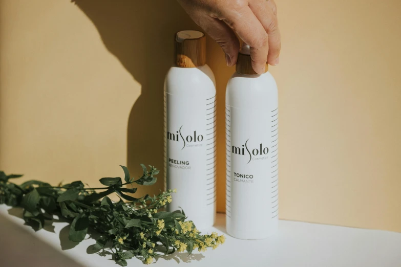 a person holding a bottle of lotion next to a bottle of lotion, by Miyamoto, trending on unsplash, lyco art, filled with plants, white limbo, background image, mirka andolfo