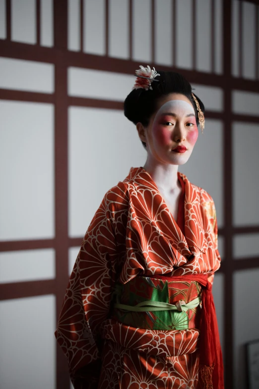 a woman in a kimono standing in front of a wall, a portrait, inspired by Uemura Shōen, trending on unsplash, ( ( theatrical ) ), square, elaborate patterned makeup, kyoto studio