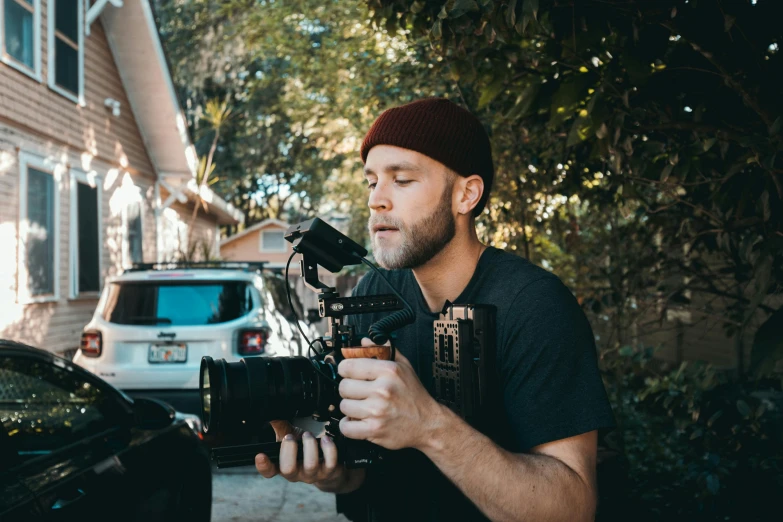 a man holding a camera in front of a car, sony fx 6, avatar image