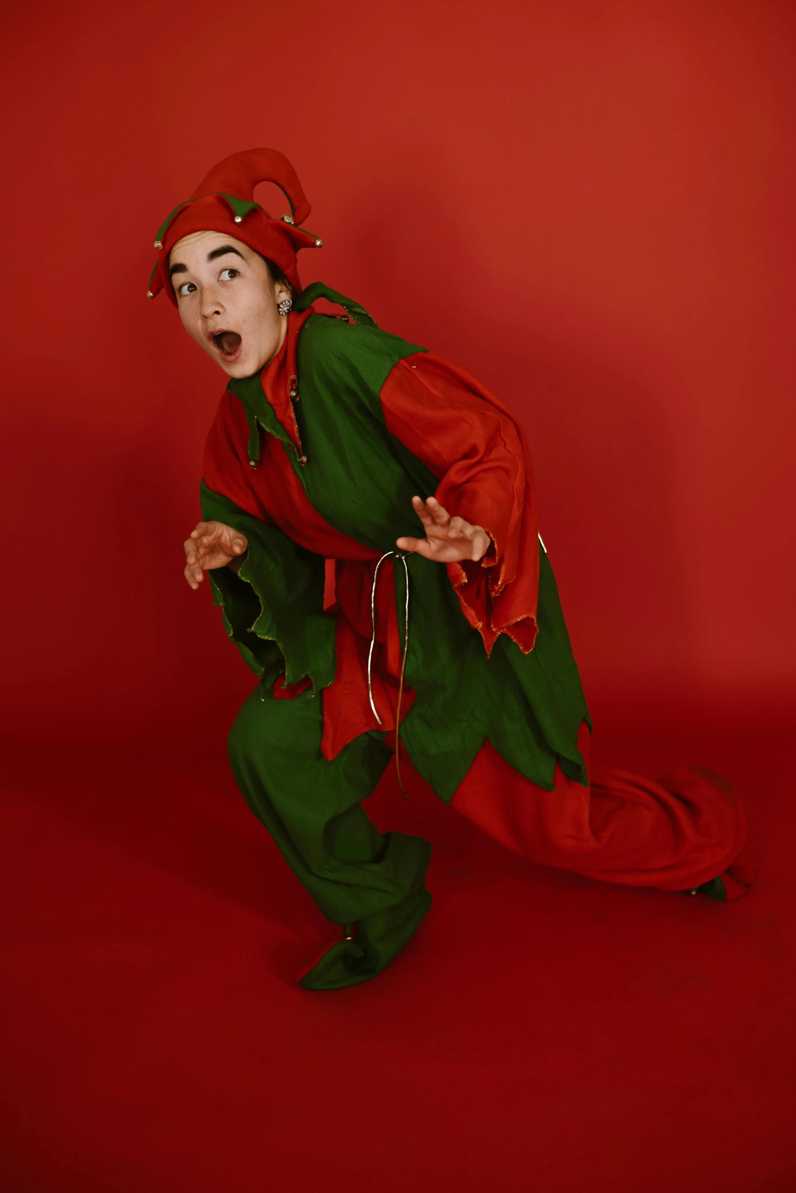 a man dressed in a red and green costume, an album cover, by Lucette Barker, pexels, male jester, expressive pose, teen elf, actress